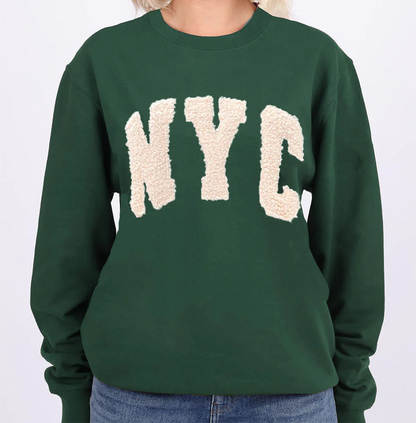 Person wearing a green sweatshirt with 'NYC' on it against a white background