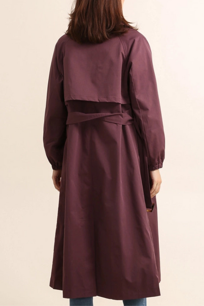  Woman wearing a becky burgundy trench coat over a black sweater and dark jeans on a plain background by penn and reid boutique leighton buzzard