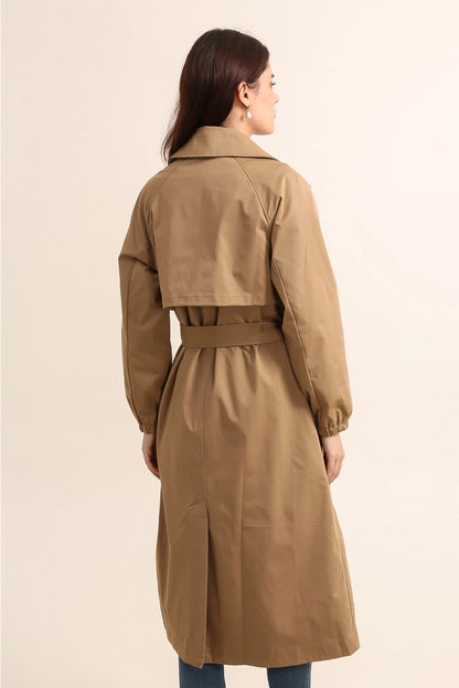 Woman wearing gale camel beige trench coat on a beige background - by penn and reid boutique leighton buzzard